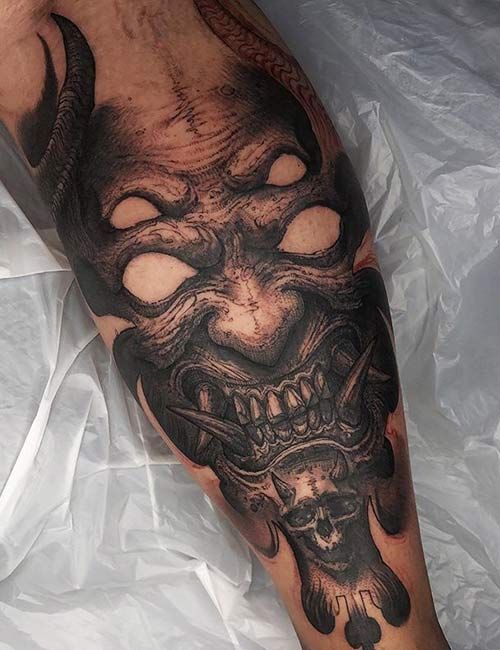 a man's leg with a demon tattoo on it and a skull in the middle