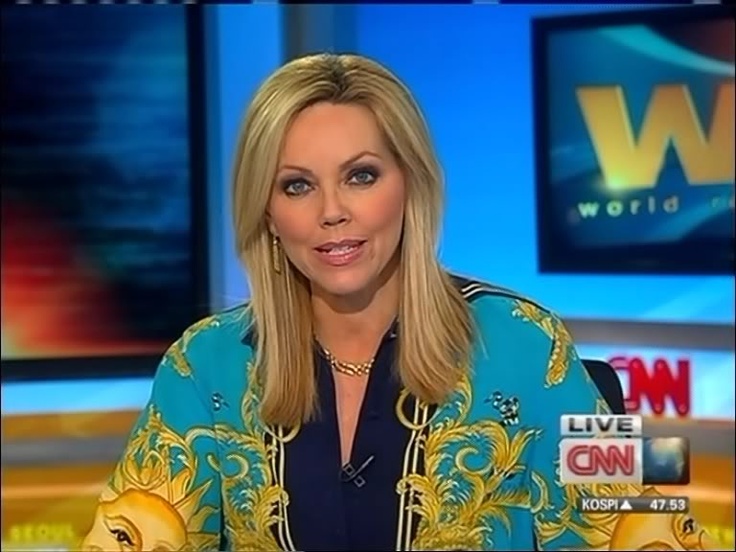 a woman is sitting down on the news with her hand in her pockets and wearing a blue shirt