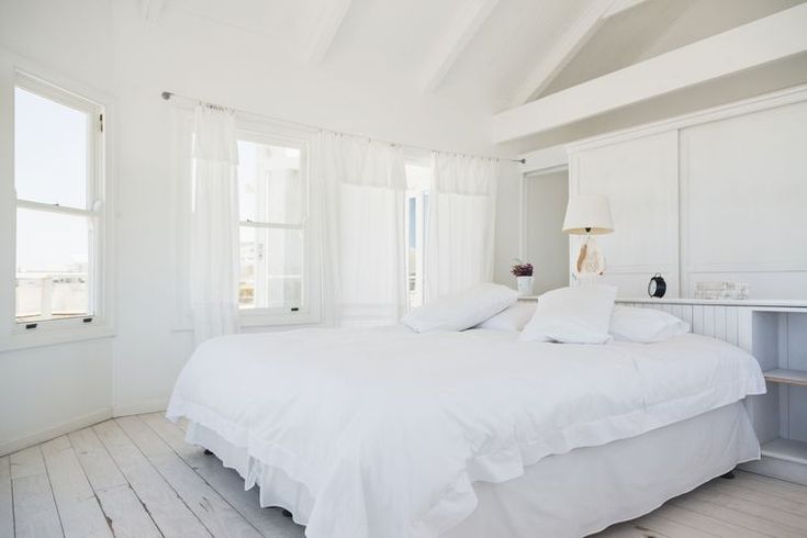 a bedroom with white bedding and windows