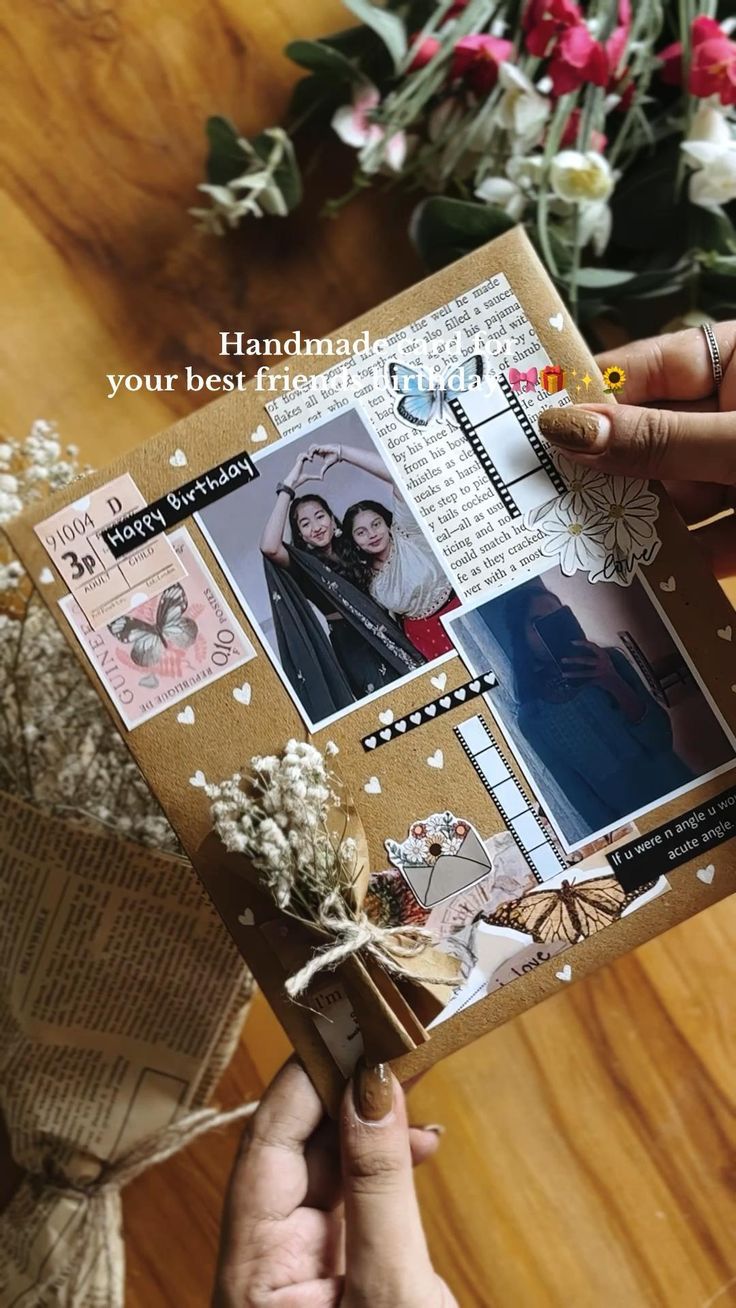 a person holding up a card with pictures on it and flowers in the back ground