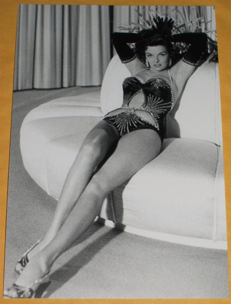 a black and white photo of a woman in a bathing suit sitting on a couch