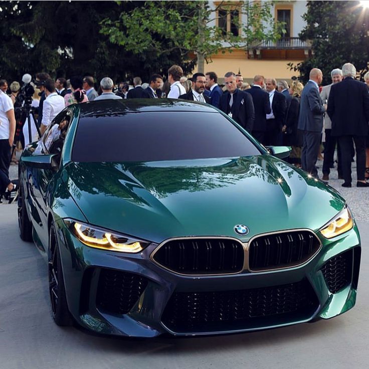 a group of people standing around a green car