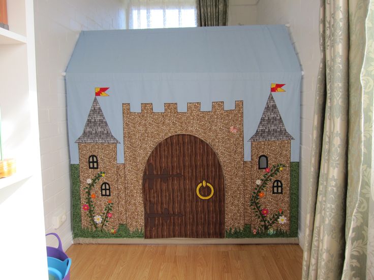 a child's play room with a castle theme on the wall and wooden floors