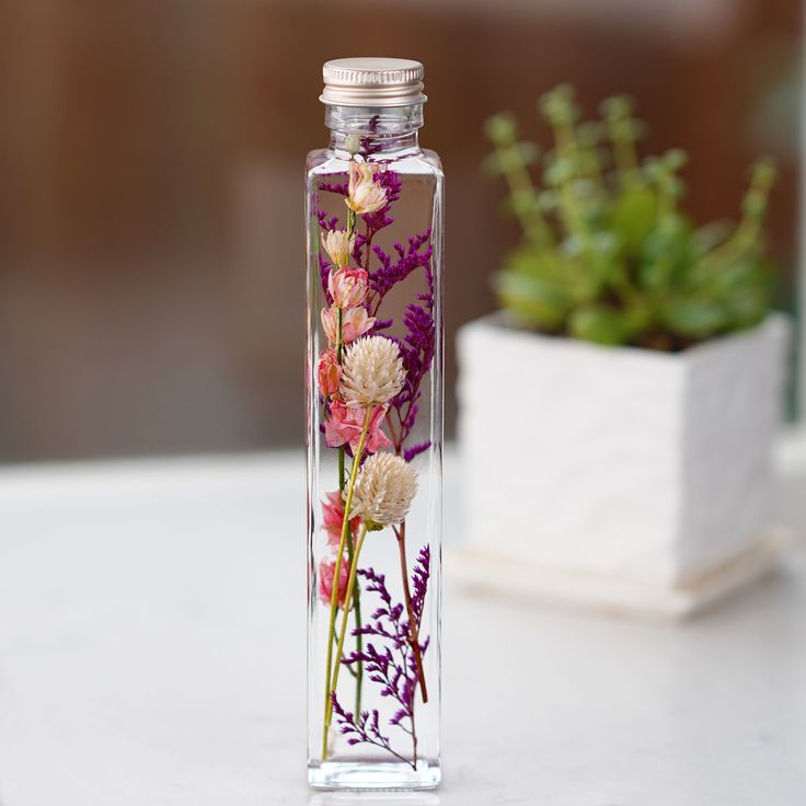 a glass bottle with flowers in it sitting on a table