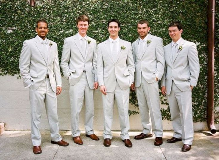 a group of men standing next to each other wearing white suits and brown derby shoes