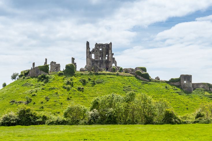 an old castle sitting on top of a lush green hillside