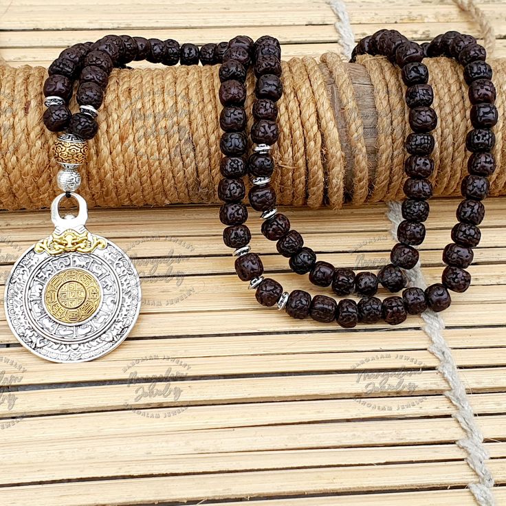 🌟 Welcome to our enchanting collection! Dive into the rich spiritual heritage with our stunning 108 Nepali Aged Black Rudraksha Beads Necklace! 📿 Each bead in this necklace carries the essence of time, aged to perfection to enhance its sacred energy and spiritual potency. 🌿 ✨ At the heart of this divine necklace lie two Om metal beads--one nestled at the midway point and another adorning the end of the mala. The Om symbol, representing the universal sound of creation, serves as a beacon of se Traditional Necklaces With 8mm Beads For Rituals, Traditional Jewelry For Meditation With 8mm Beads, Spiritual Silver Beaded Necklaces For Puja, Spiritual Necklaces With Silver Beads For Puja, Traditional 8mm Beads Jewelry For Meditation, Traditional Jewelry With 8mm Beads For Meditation, Silver Spiritual Mala For Meditation, Silver Mala With 108 Beads For Meditation, Spiritual Silver Mala For Meditation