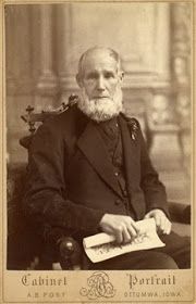 an old black and white photo of a man with a beard sitting in a chair