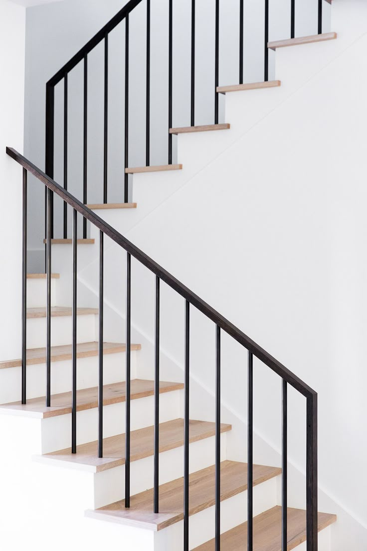 a white staircase with wooden handrails and black rails