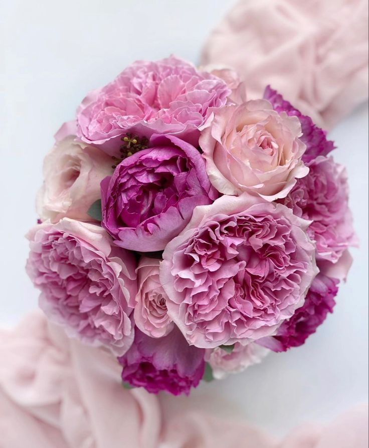 a bouquet of pink peonies on a white surface