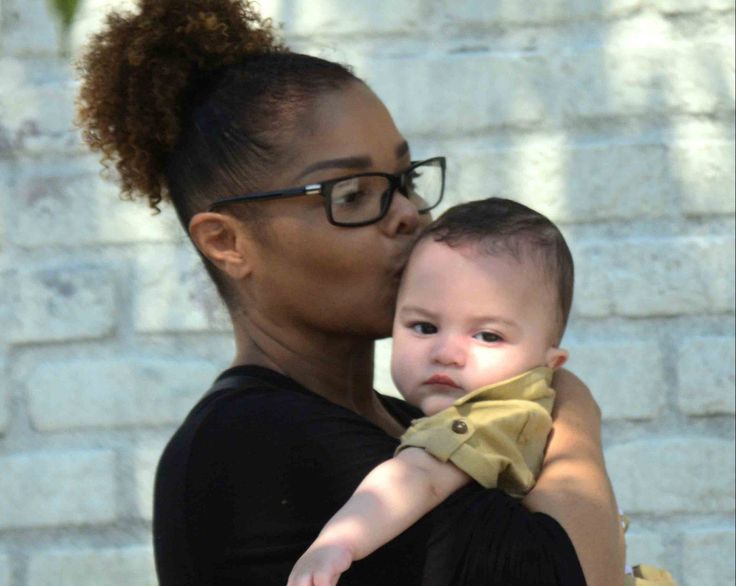 a woman holding a baby in her arms and kissing it's face with glasses on