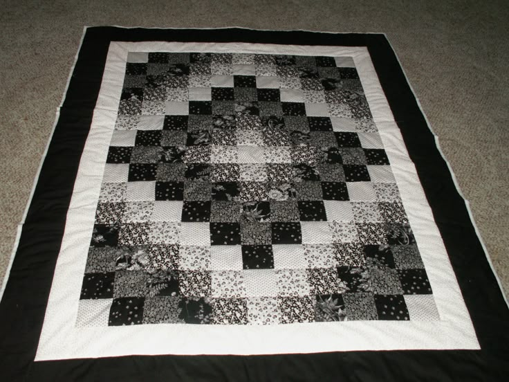 a black and white quilt is laying on the floor