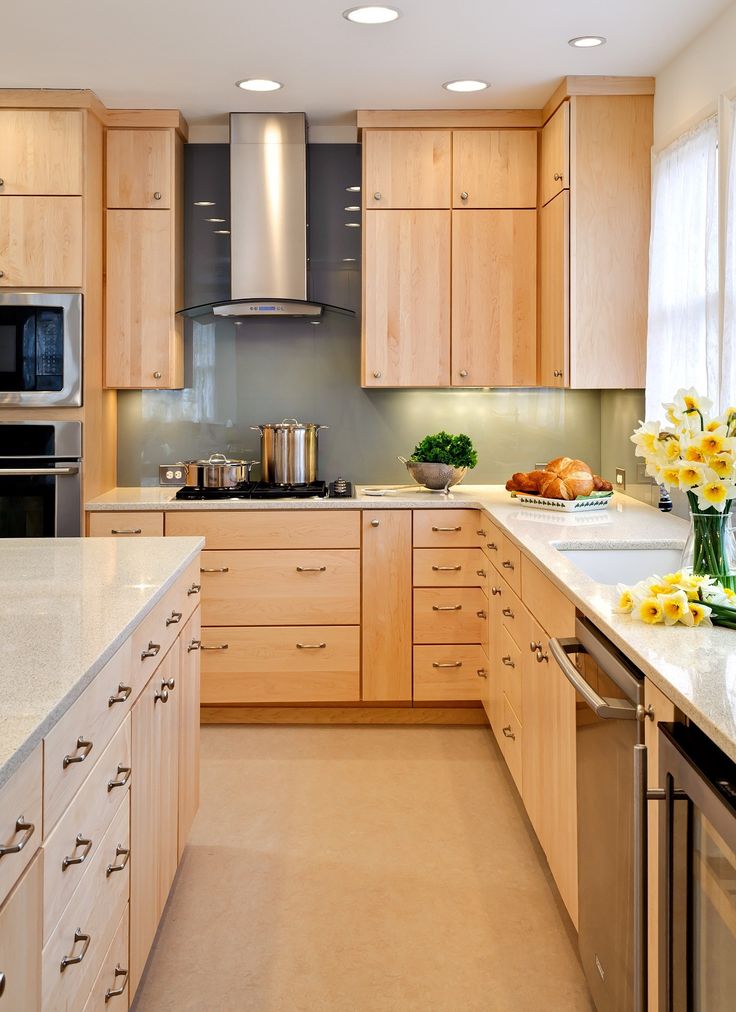 a large kitchen with wooden cabinets and stainless steel appliances, along with yellow flowers in vases on the counter