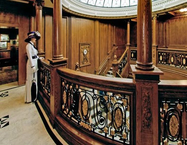 a woman standing in front of a staircase with a clock on the wall behind her