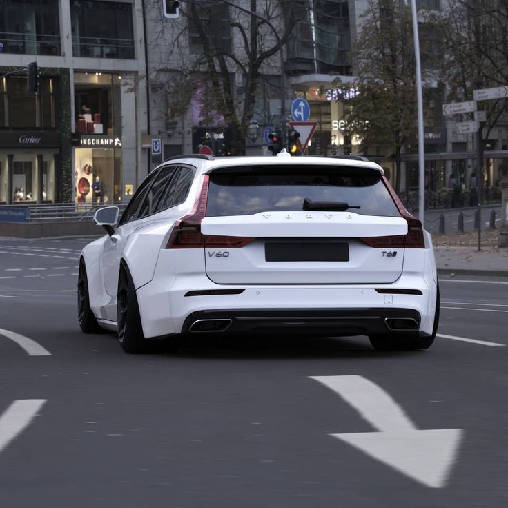 a white car driving down a street next to tall buildings