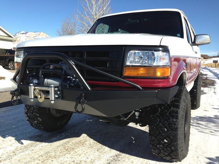 the front end of a white truck parked on snow covered ground