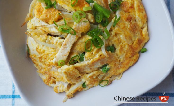 a white plate topped with an omelet covered in meat and veggies