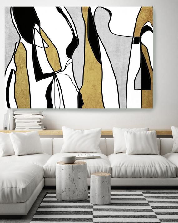 a modern living room with white couches and black and gold artwork on the wall