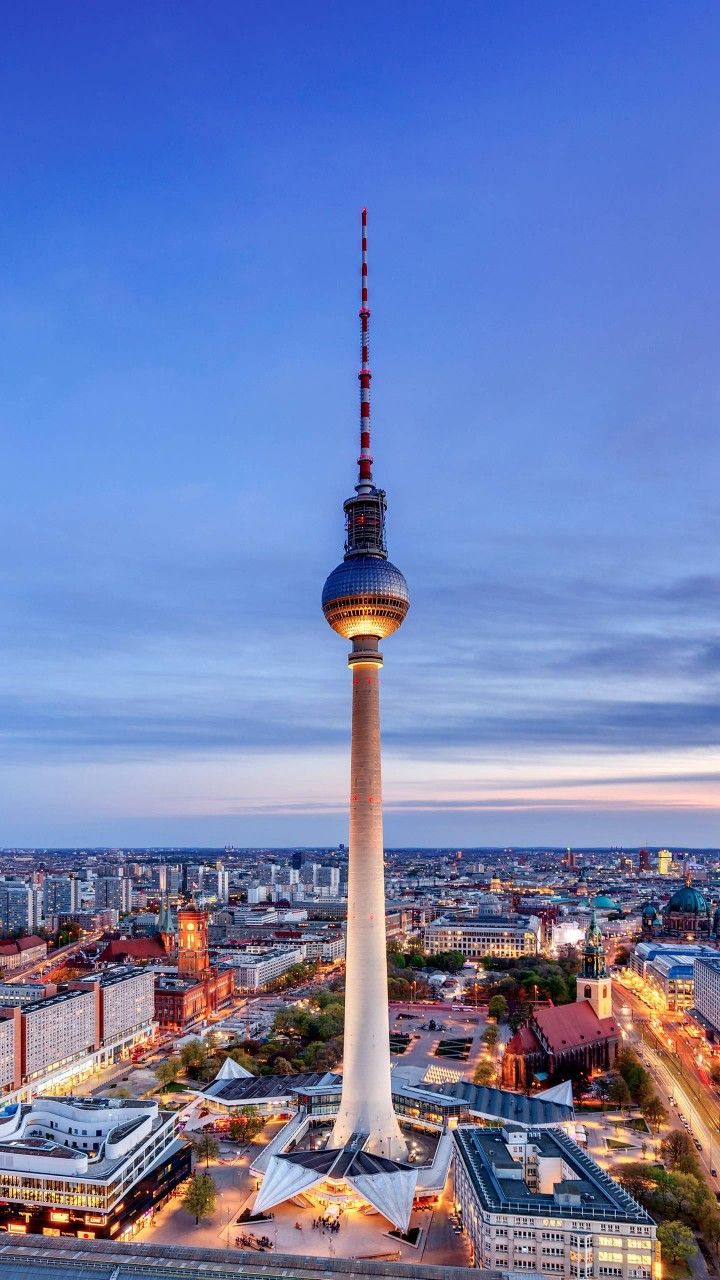 the television tower in berlin, germany is lit up at night with its lights on