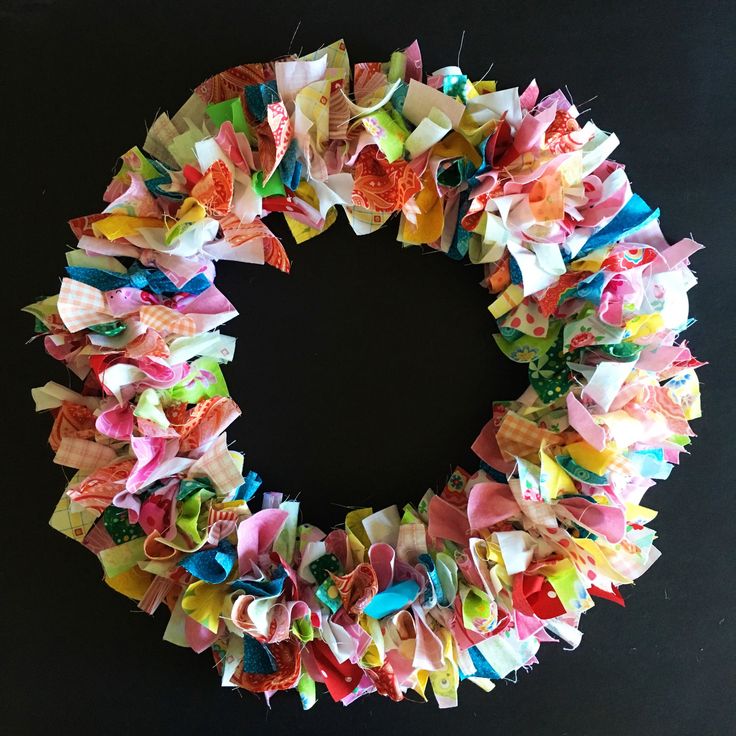 a close up of a wreath made out of different types of paper flowers on a black background