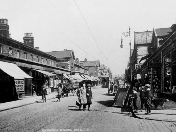 an old black and white photo of people walking down the street in front of shops