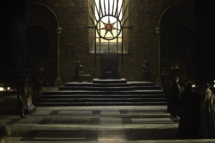 the iron throne sits in front of a stained glass window at night, with people standing around it