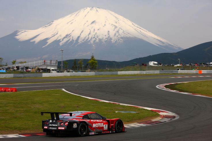 a race car driving on a track with a mountain in the background