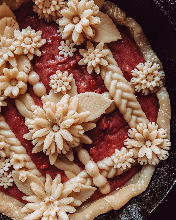 an uncooked pie with flowers and leaves on top