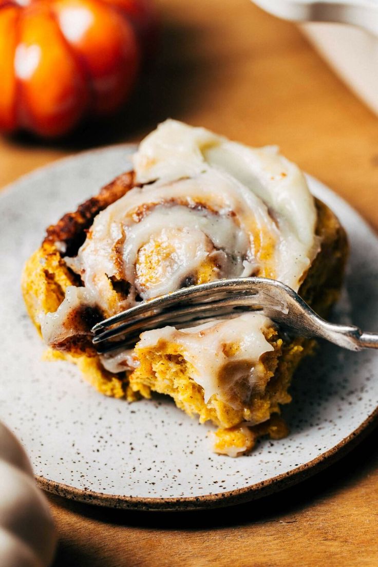 a piece of cinnamon roll sitting on top of a plate with a fork in it