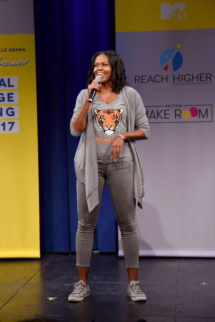 a woman standing on top of a stage with a microphone in her hand and an orange tiger t - shirt