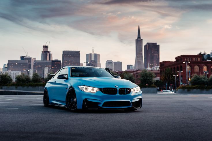 a blue car parked in front of a city skyline