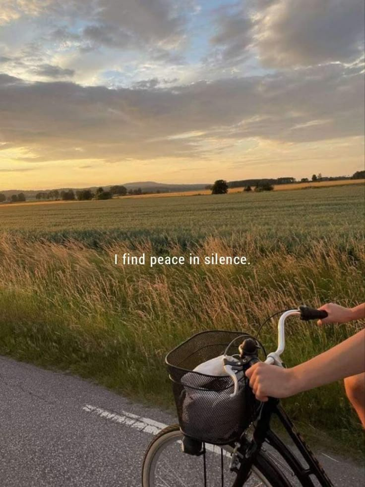 a person riding a bike down a road with the words i find peace in silence