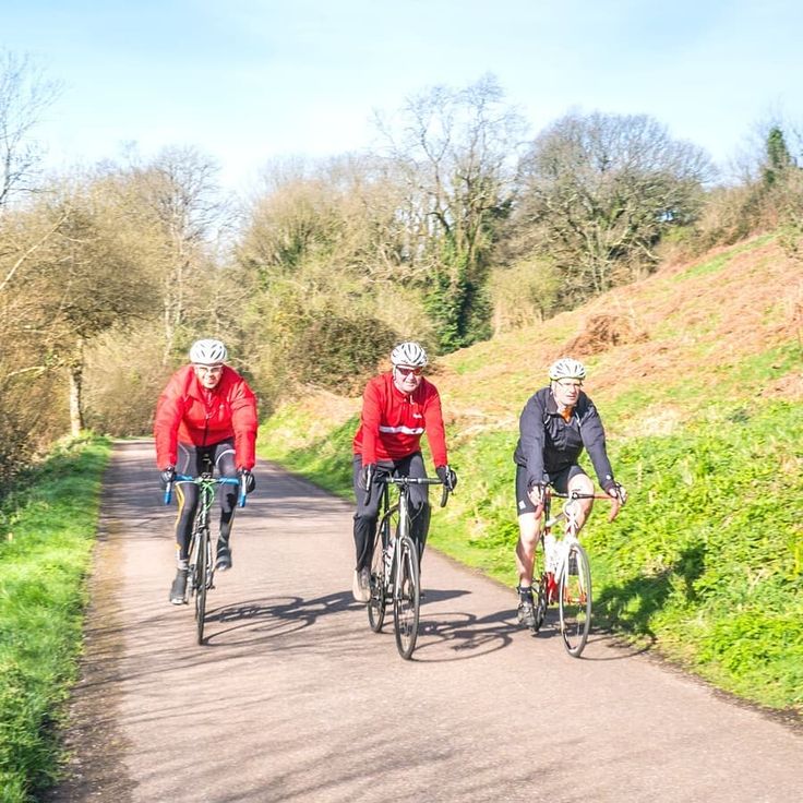 three people riding bikes down a country road