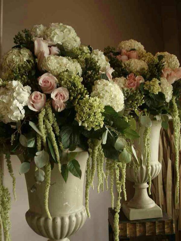 three white vases filled with flowers on top of a table