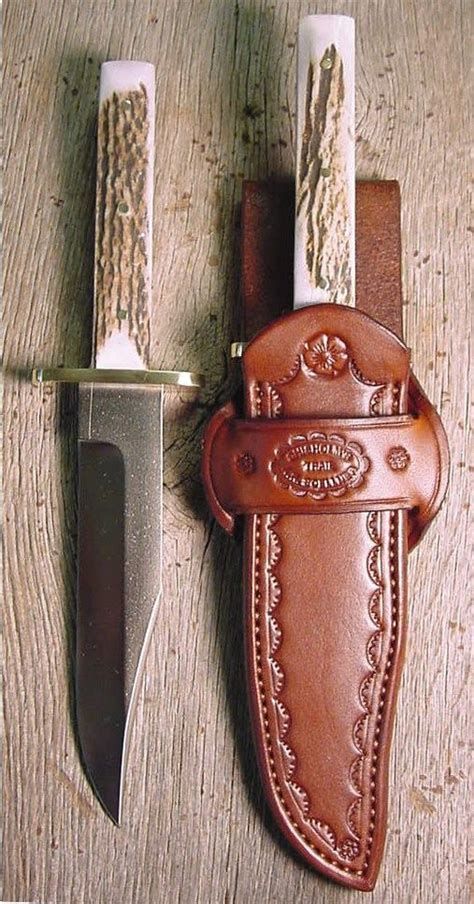 a knife and sheath sitting next to each other on a wooden table with two knives in it