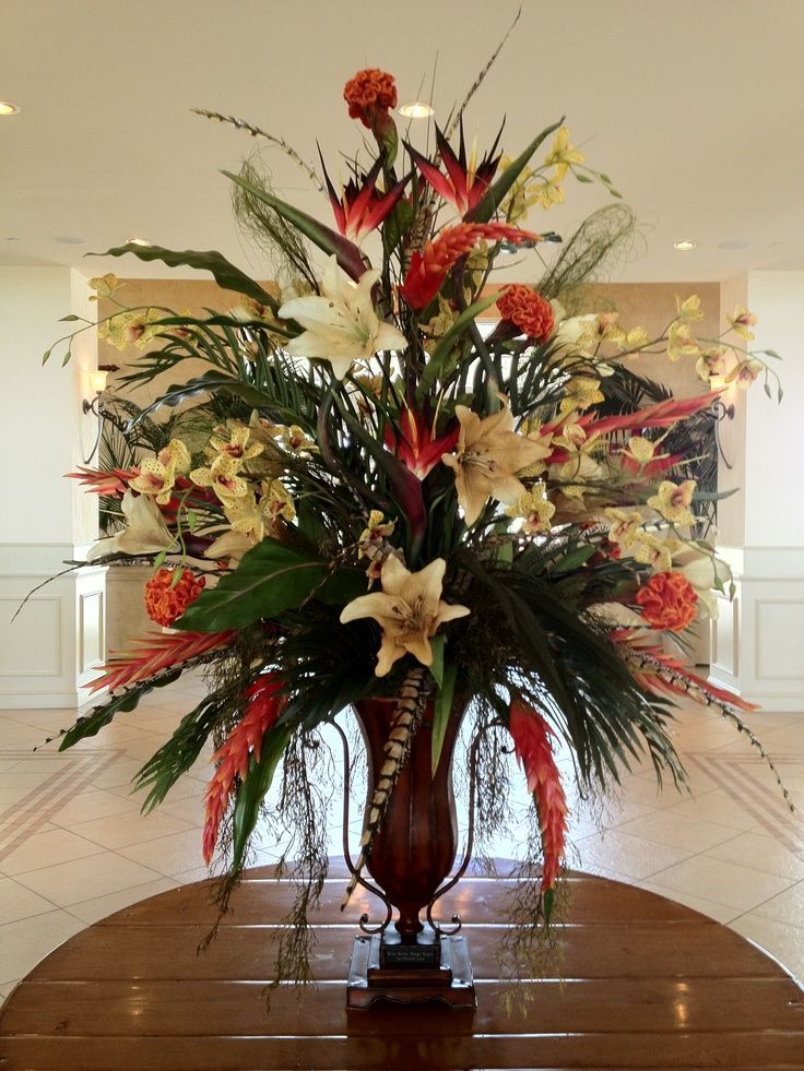 a vase filled with lots of flowers on top of a wooden table in a room