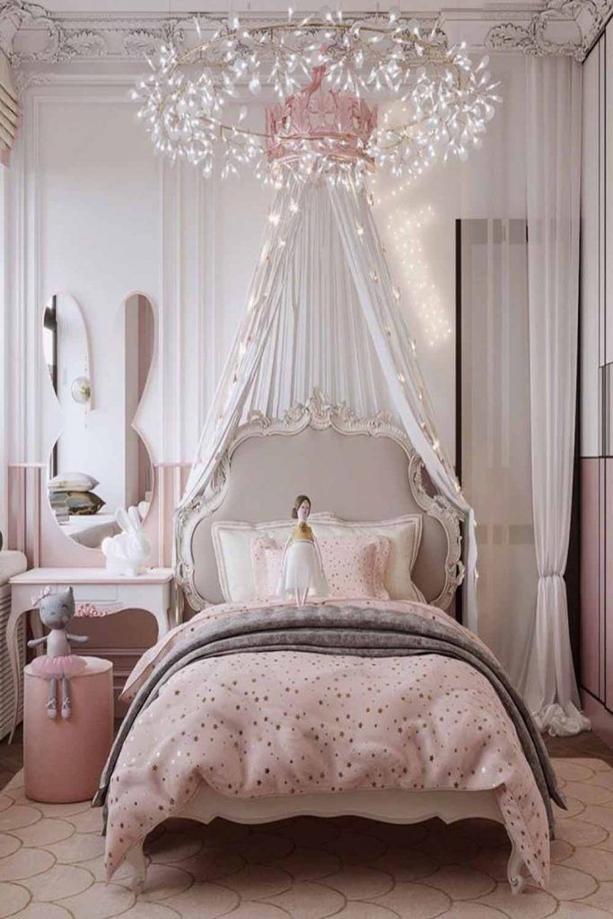 a pink and white bedroom with a chandelier hanging from the ceiling above the bed