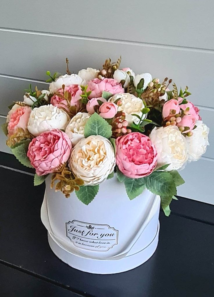 a white bucket filled with pink and white flowers