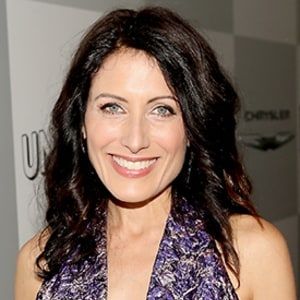 a woman with long dark hair smiling at the camera and wearing a purple dress,