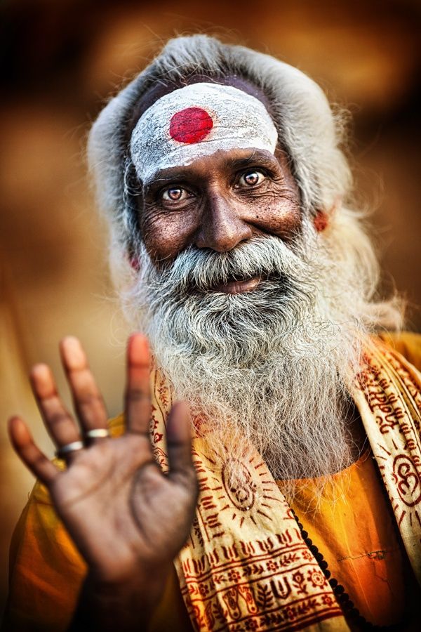 an old man with white hair and a red dot on his forehead is making the peace sign