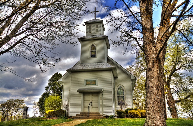 a white church with a steeple surrounded by trees