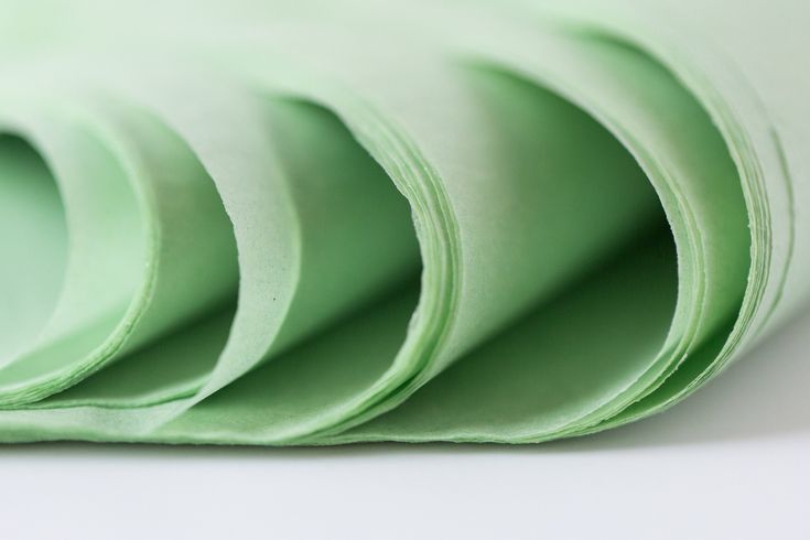 several pieces of green paper folded together on a white surface