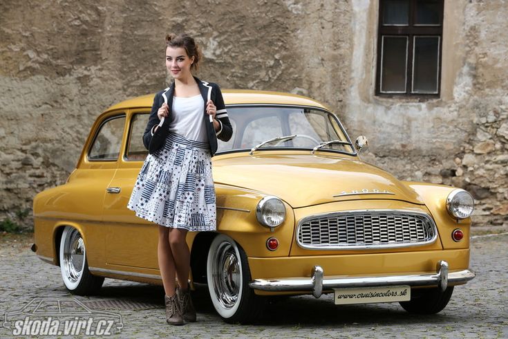 a woman standing next to an old yellow car