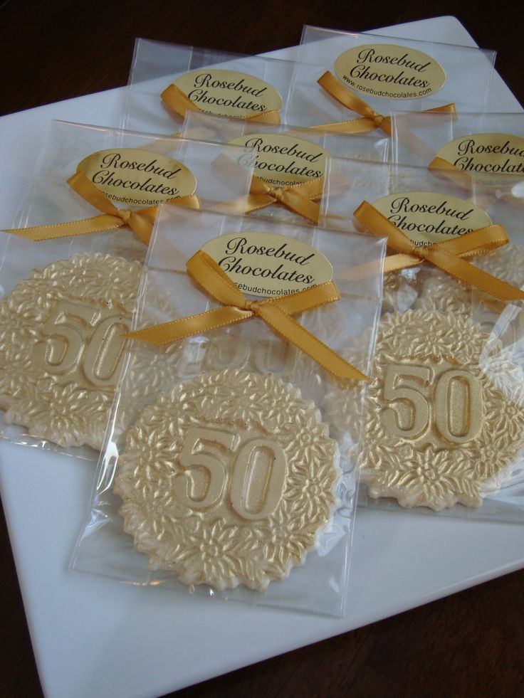 there are some cookies that have been decorated with ribbons and bows on the table for someone's 50th birthday