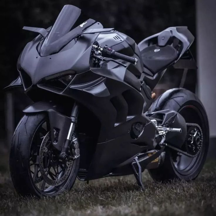 a black motorcycle parked on top of a lush green field