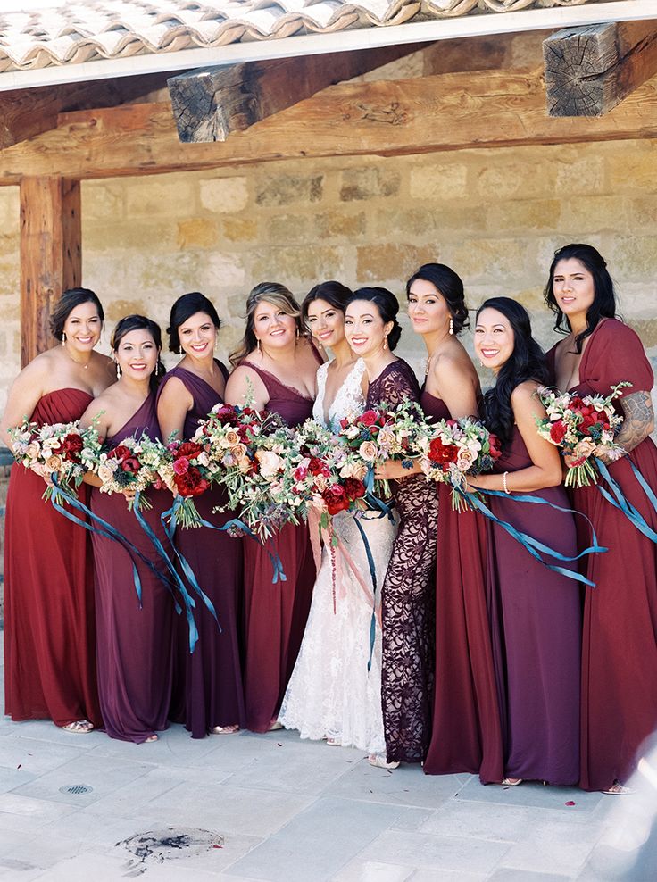 a group of women standing next to each other wearing dresses and holding bouquets in their hands