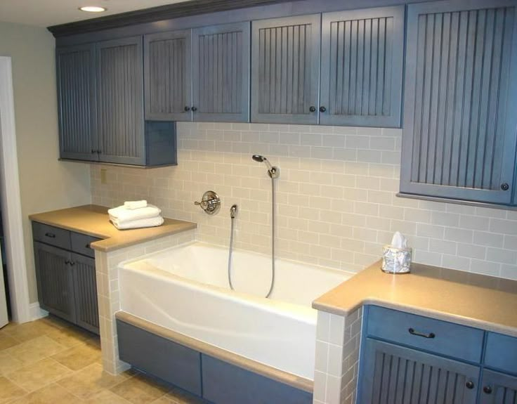 a bathroom with gray cabinets and a white bathtub in the middle of the room