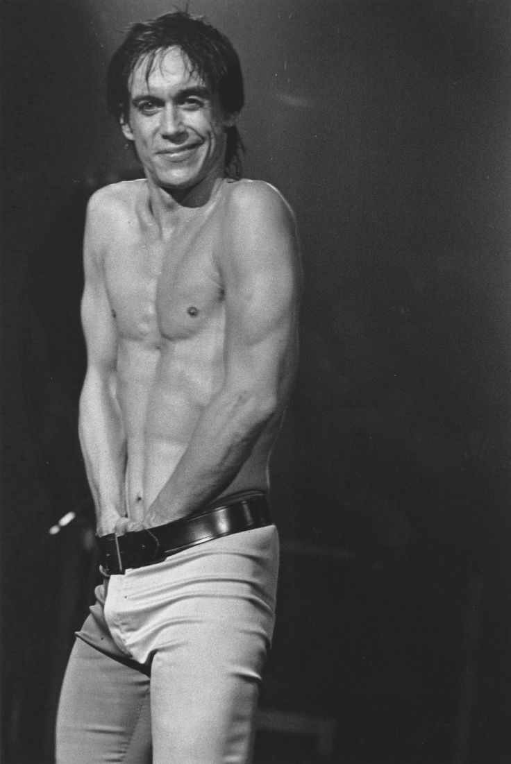 a shirtless man standing on stage with his hands in his pockets