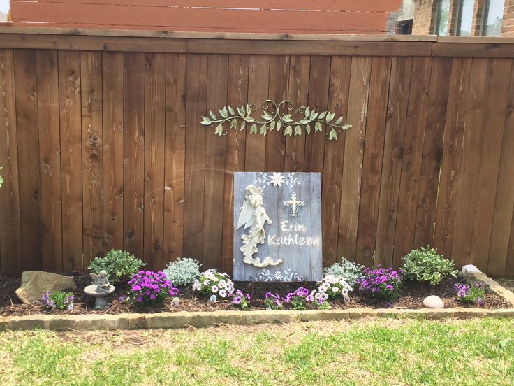 a wooden fence with a sign and flowers on it