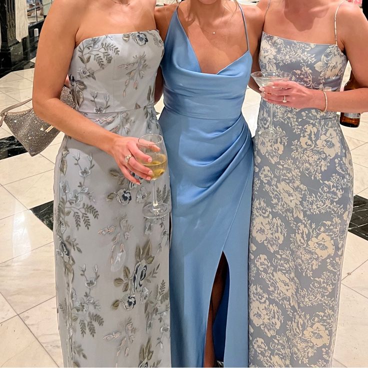 three women standing next to each other in dresses